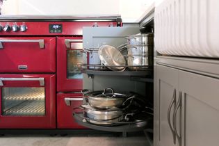 Shaker kitchen featuring a red double range with stainless steel knobs and neatly organised pull out shelves holding pots and pans.