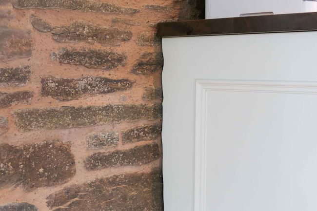 White shaker cabinet up against brick wall, showing the scribing against the wall. 