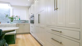 A Shaker kitchen with light-coloured cabinetry, a quartz countertop, and a kitchen island with seating.