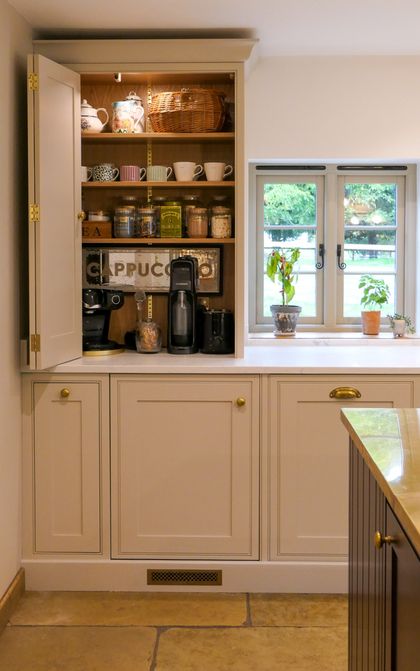 Counter-top cupboard with bi-fold door open, storing glassware with worktop space