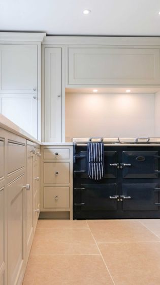Shaker kitchen interior with cream cabinetry and a dark stove. A striped dish towel hangs from the stove, creating a clean and elegant ambiance.