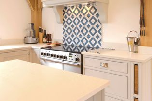 Shaker kitchen with light grey cabinets, a sleek stainless steel stove, and a blue geometric tile backsplash. An inviting atmosphere.
