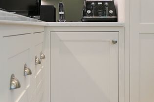 White kitchen cabinets with silver handles, a black toaster, and a cordless phone on the countertop create a clean and modern aesthetic.