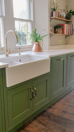 Up close of the farmhouse style open front sink, with a plant on the window sill.