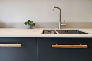 Close up of dark blue kitchen, sink with silver tap