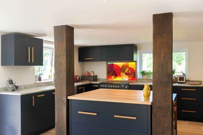 Navy slab kitchen with an oak-topped island framed by reclaimed timber posts