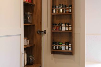Fitted walnut larder shelving with a built-in door spice rack and storage jars