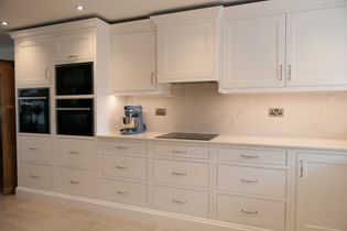 White shaker kitchen cabinetry with a black double oven and blue mixer on the left of the hob