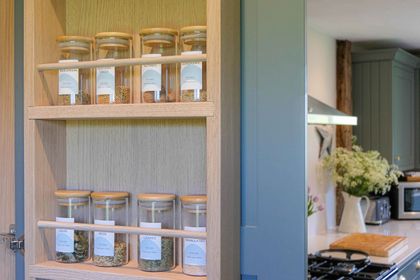Built-in oak spice rack with labelled glass jars inside a larder