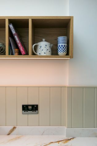 Open wooden shelving with books and vases on, LED lighting underneath