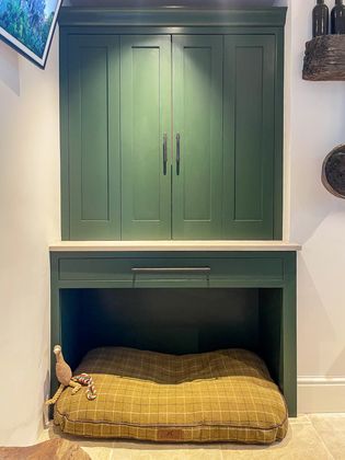 Built in yellow dog bed within the shaker cabinetry underneath the green countertop cupboard.