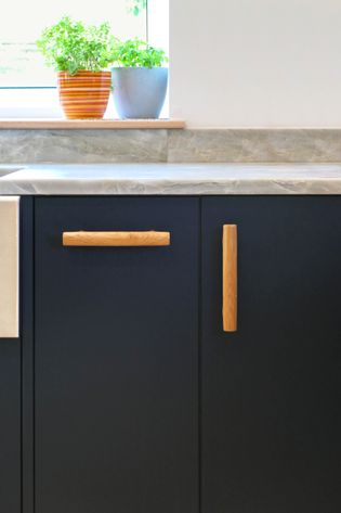 Close up of navy blue kitchen cabinet showing the solid oak bar handles and granite worktop