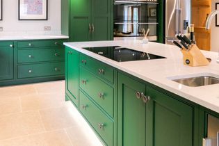 Shaker kitchen with sleek green cabinets, white worktop, and light beige tile flooring. Features a induction hob, sink, and knife set, conveying a fresh vibe.