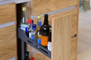 Modern oak narrow pull out cabinet with condiments on the shelves