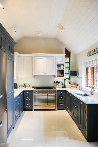 Bright kitchen with white walls and ceiling, navy blue cabinets, and a large oven. Sunlight streams through a window, creating a cozy, inviting atmosphere.