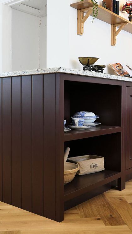 Deep burgundy Shaker cabinet end with tongue-and-groove panelling and open shelves of china plates