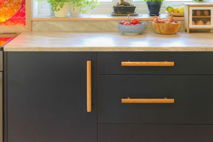 Navy slab drawers and a door with oak bar handles beneath a marble worktop