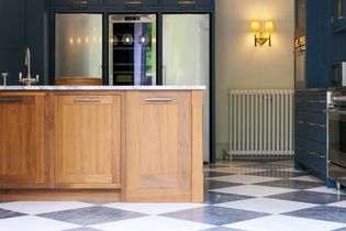 A Shaker kitchen featuring wooden cabinetry, a marble countertop, a bright interior with blue accents, a refrigerator, and a checkerboard floor pattern.