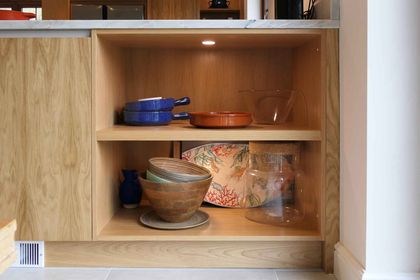 Open oak shelving with crockery, bowls and a glass jar on display
