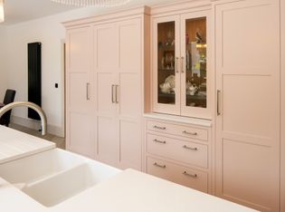 Soft pink run of Shaker cabinetry, with a glass fronted two door cupboard