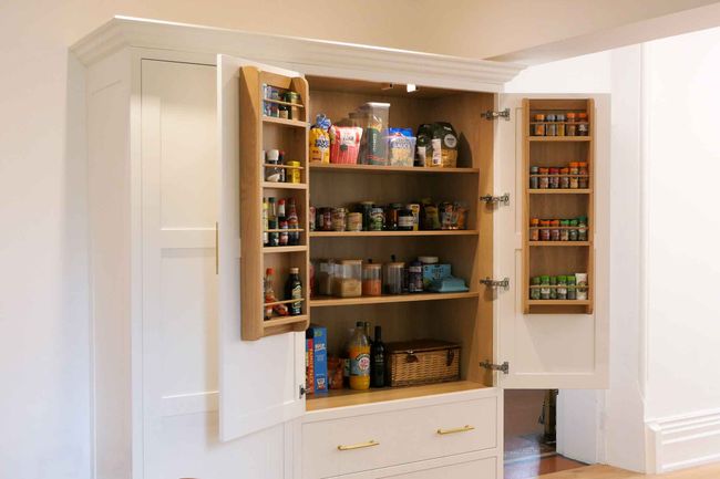 a handcrafted bespoke shaker kitchen painted in a bright white colour, featuring a tall larder cupboard