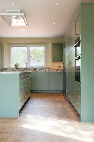 Shaker kitchen with sage green cabinets, granite worktop, and large window. Bright lighting and earthy tones create a calm, inviting space.