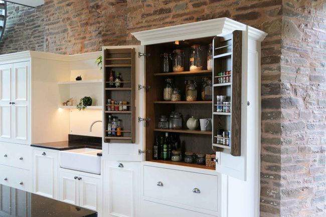 a handcrafted bespoke shaker kitchen featuring a beautiful larder cupboard painted in a soft white colour and crafted in dark walnut wood