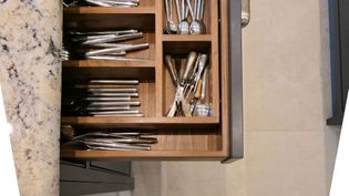 A well organised cutlery drawer with a dark grey frame and nickel handle.