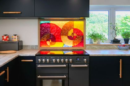 Navy slab kitchen with a range cooker and a vibrant stained-glass splashback