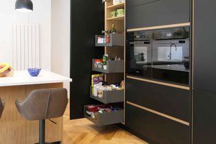 Modern kitchen with a white marble countertop, stainless steel sink, and sleek faucet. A knife block and sunflowers add warmth. Large window with garden view.