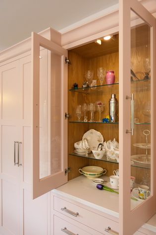 Open glassware cupboard showing a mixture of different glasses, vases and crockery