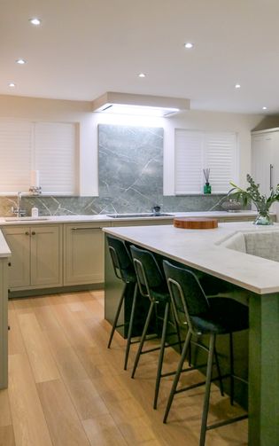A Shaker kitchen featuring sleek cabinets, an island with bar stools, and elegant lighting.