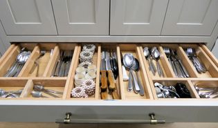 A kitchen drawer filled with various utensils and cutlery organised in wooden dividers.
