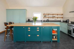 Shaker kitchen with a sleek central island, deep blue cabinetry, and a pantry stocked with spices and condiments; bright and organized ambiance.