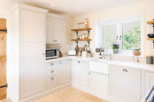A dark grey kitchen cabinet with a pull-out pantry features organised shelves of canned goods and snacks. 