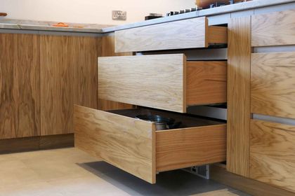 Open oak drawers showing dovetailed drawer boxes and the handleless pull-to-open detail