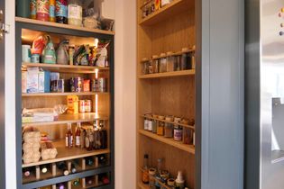 Wooden pantry shelves filled with various food items, spices, and bottles. Neatly organized, creating a sense of order and accessibility.