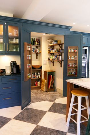 A Shaker kitchen with a pantry area featuring organised shelves of spices and other items, blue cabinetry, and a quartz countertop.