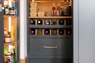A pantry with organized shelves holds egg cartons, sauce bottles, and a wine rack filled with assorted wine bottles, conveying order and sophistication.