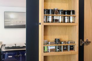 Custom spice rack inside navy blue cabinet which is opened
