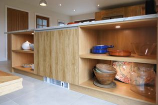 Open shelving in the peninsular with different bowls and plates on the shelves.