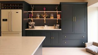 Shaker kitchen with sleek design, featuring dark grey cabinetry, a beige marble countertop, a white fridge, and open shelves with decor items. Cozy and elegant.