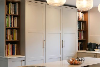 Hand-painted white larder cupboards framed by built-in cookbook shelves