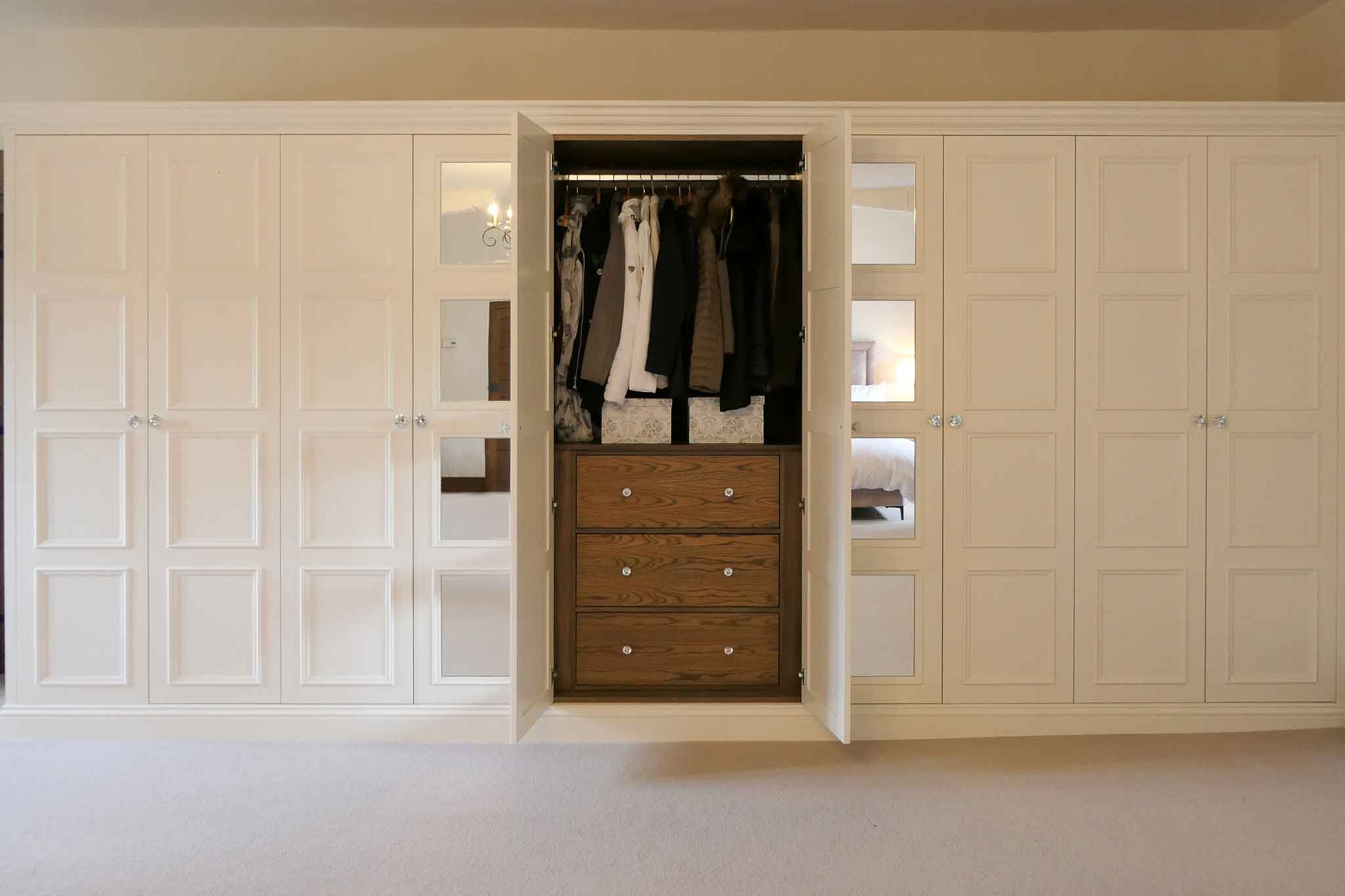 White bespoke mirrored wardrobes with walnut cabinets