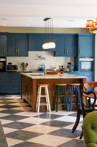 A Shaker kitchen with blue cabinets, a large island, and a black-and-white checkered floor.