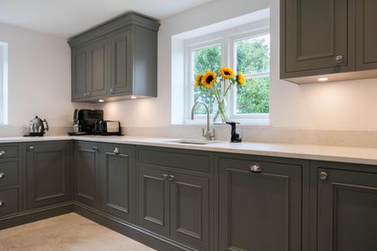 Grey Shaker kitchen with wall cabinets and a window above the sink