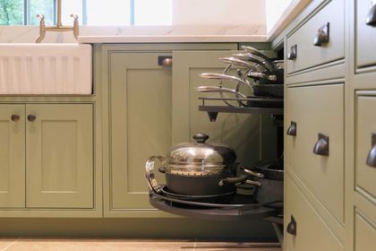 Pull-out corner unit holding pots and pans in a sage green kitchen