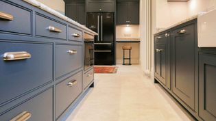 Shaker kitchen featuring navy blue cabinets with silver handles, beige tile flooring, black double fridge, and ambient lighting.