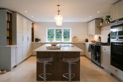 White Shaker kitchen with a walnut island, quartz worktop and acrylic bar stools