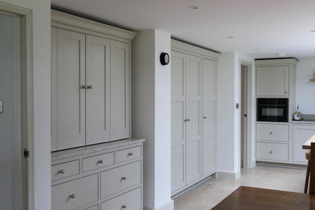 Spacious shaker kitchen featuring elegant white cabinets, a built-in oven, and a stone countertop. The room is bright and clean with a minimalist design.